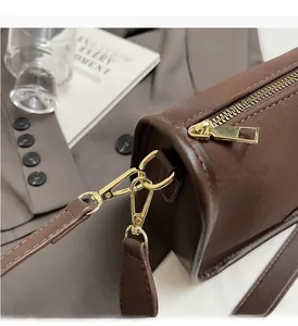 Close-up of luxury gold hardware and polished zipper on dark brown leather handbag