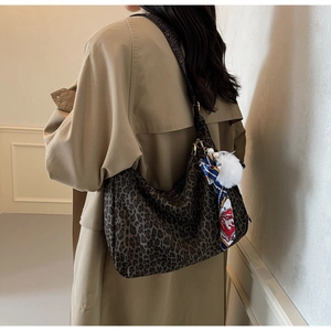 Sac hobo à imprimé léopard avec foulard en soie bleu porté sur un trench-coat