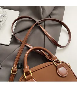 Détail du sac en cuir marron avec garnitures dorées et bandoulière réglable fine