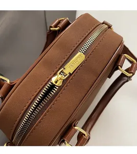 Détail de la fermeture éclair dorée sur le sac à main marron en cuir synthétique