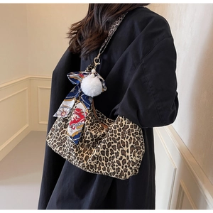 Détail du sac léopard avec foulard en soie élégant et pendentif pompon blanc