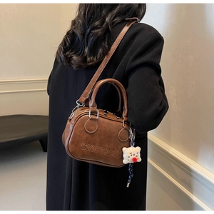 Détail du sac à bandoulière en similicuir marron avec breloque ours en peluche sur la sangle
