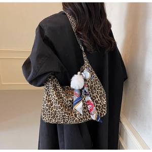 Détail du sac cabas léopard avec pompon en peluche et foulard en soie sur un manteau