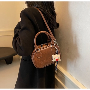 Sac à main vintage marron avec charm ours en peluche porté par un mannequin de dos