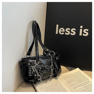 Detail of black glossy patent leather shoulder bag with silver chain and white typography