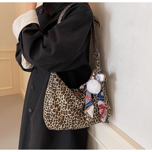 Vue détaillée du sac hobo léopard avec foulard en soie coloré et pompon en fourrure blanc