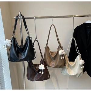 Détail de grands sacs hobo en similicuir en quatre couleurs avec pendentifs nuage