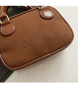 Détail d'un sac cabas marron foncé avec logo en relief et finitions dorées