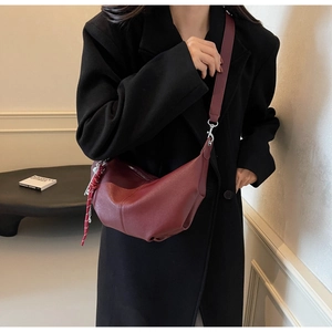 Detail of burgundy PU leather hobo bag with braided strap and silver metal zipper