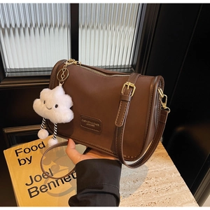 Detail view of brown leather boston bag with gold buckle and white cloud charm
