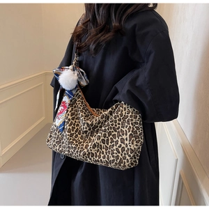Détail du sac cabas léopard avec pompon blanc et foulard en soie sur la bandoulière