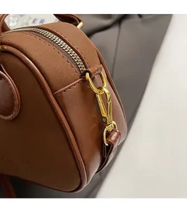 Gros plan détaillé sur le fermoir en métal doré et le zip d'un sac à main en cuir marron