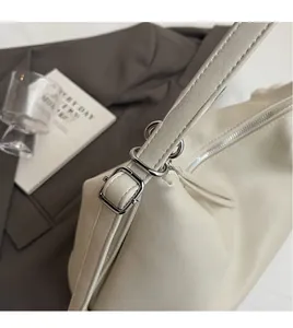 Détail de la bandoulière réglable et des ferrures argentées sur un sac en cuir beige