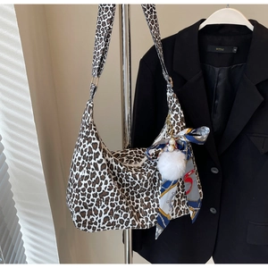 Détail du sac hobo en toile léopard avec foulard en soie bleue et pompon blanc en peluche