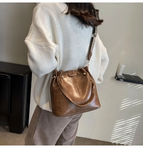 Detail of brown vintage leather bucket bag with magnetic closure and patterned strap