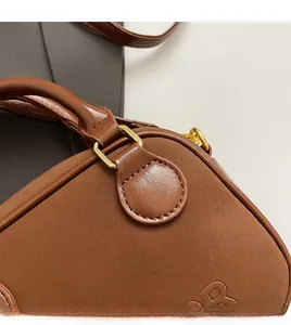 Gros plan d'un sac à main en daim marron avec coutures renforcées et boucles dorées