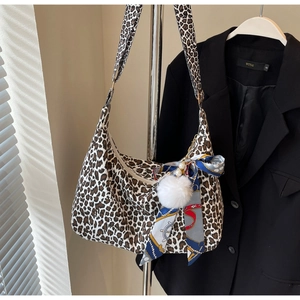 Gros plan sur un sac cabas léopard en toile avec pompon peluche et foulard décoratif