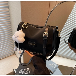 Detailed view of black nylon pillow bag with gold logo and soft cloud plush keychain