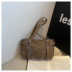 Close-up of retro brown shoulder bag featuring silver chain and artistic text detail