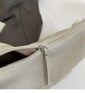 Détail de la fermeture éclair en métal argenté et tirette en cuir sur sac crème