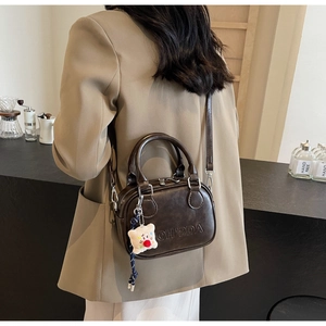 Sac Boston vintage marron foncé avec embossage et charm en peluche sur mannequin femme