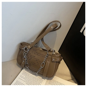 Detailed close-up of brown glossy shoulder bag with chain strap resting on a book