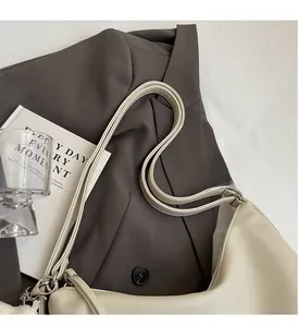 Gros plan du sac à bandoulière en cuir PU crème sur un blazer marron élégant
