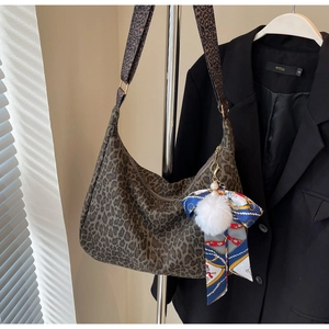Détail du sac cabas léopard avec un pendentif en peluche et un ruban de soie décoratif