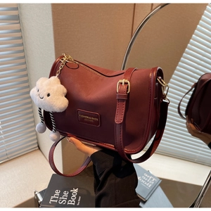 Close-up of deep wine red leather pillow bag with gold buckles and white cloud plush charm