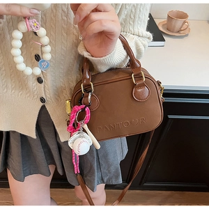 Brown vintage faux leather crossbody bag detail with sports-themed keychain and brand logo