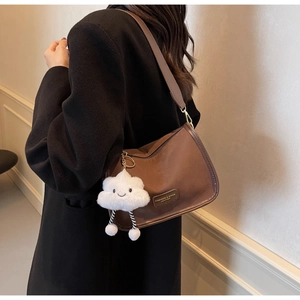 Close-up of a dark brown half-moon shoulder bag with a plush white cloud charm detail