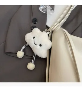 Détail d'un charm nuage en peluche blanche avec visage souriant et jambes rayées sur un sac