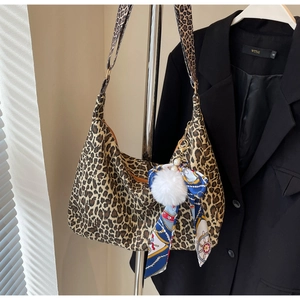 Détail du sac hobo léopard avec pompon en peluche et foulard en soie sur blazer noir