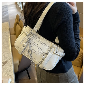 Close-up of cream leather shoulder bag featuring black script and silver chain detail