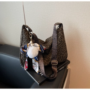 Détail du sac cabas léopard avec pompon blanc et breloque ruban coloré sur la hanse