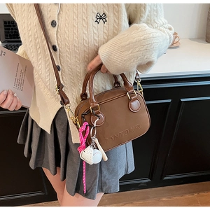 Detail of dark brown leather crossbody bag with PANTOOR embossing and baseball charm