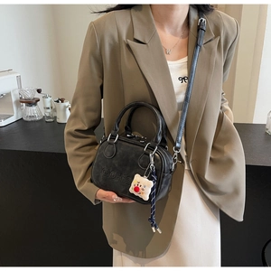 Détail du sac vintage en cuir noir avec gaufrage CIOH'2 et accessoire en peluche doux