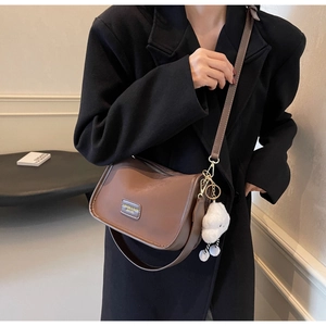 Detailed close-up of brown vintage crossbody bag with metal logo and plush cloud charm