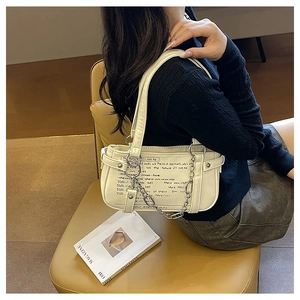 Detail view of cream shoulder bag with black lettering and elegant metal chain