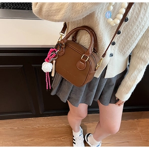 Brown leather handbag detail featuring Autoor embossed logo and baseball charm