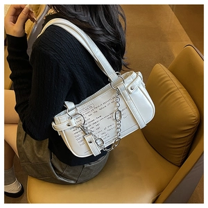 Detail of white leather shoulder bag featuring black script print and silver chain link