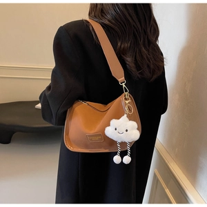 Close-up of brown PU leather shoulder bag with plush cloud charm and embossed logo