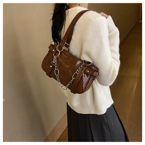 Detail of dark brown patent leather baguette bag with silver chain and text design