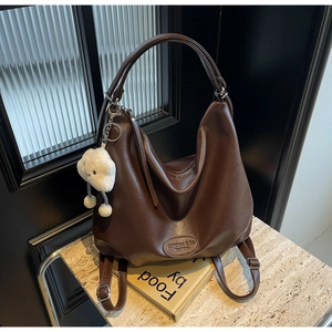 Détail du sac cabas en cuir marron foncé avec pendentif nuage et logo rond embossé