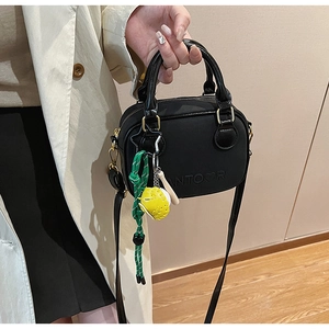 Detail view of a black mini crossbody bag with a trendy baseball charm and logo