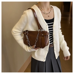 Close-up of vintage brown leather handbag with silver chain and artistic typography