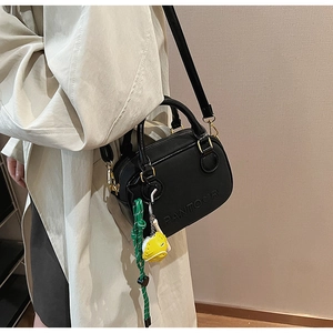 Détail du sac Boston noir avec gaufrage PANTOOR et breloque poussin jaune sur la bandoulière