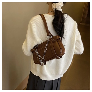 Detail view of dark brown leather shoulder bag with silver chain and retro lettering