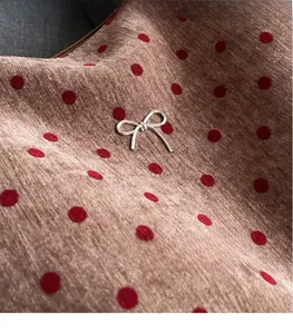 Close-up of a silver metal bow buckle on red polka dot fabric with soft texture