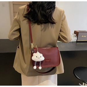 Macro detail of wine red crossbody bag featuring smooth texture and cloud plush charm